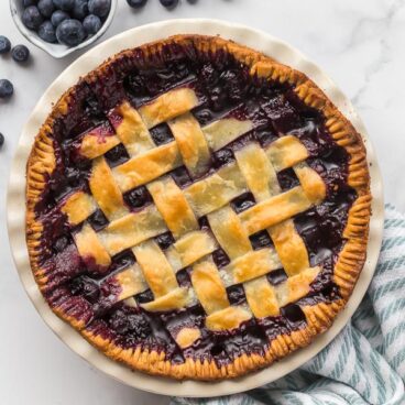 overhead image of baked blueberry pie with fresh blueberries