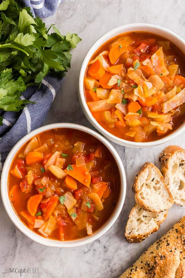 cabbage soup two bowls on grey marble overhead with crusty bread