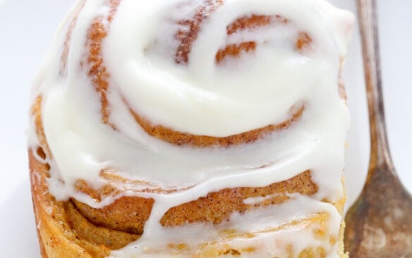 carrot cake cinnamon roll on white plate.