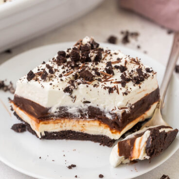 a piece of chocolate lasagna on a white plate with a fork beside it.