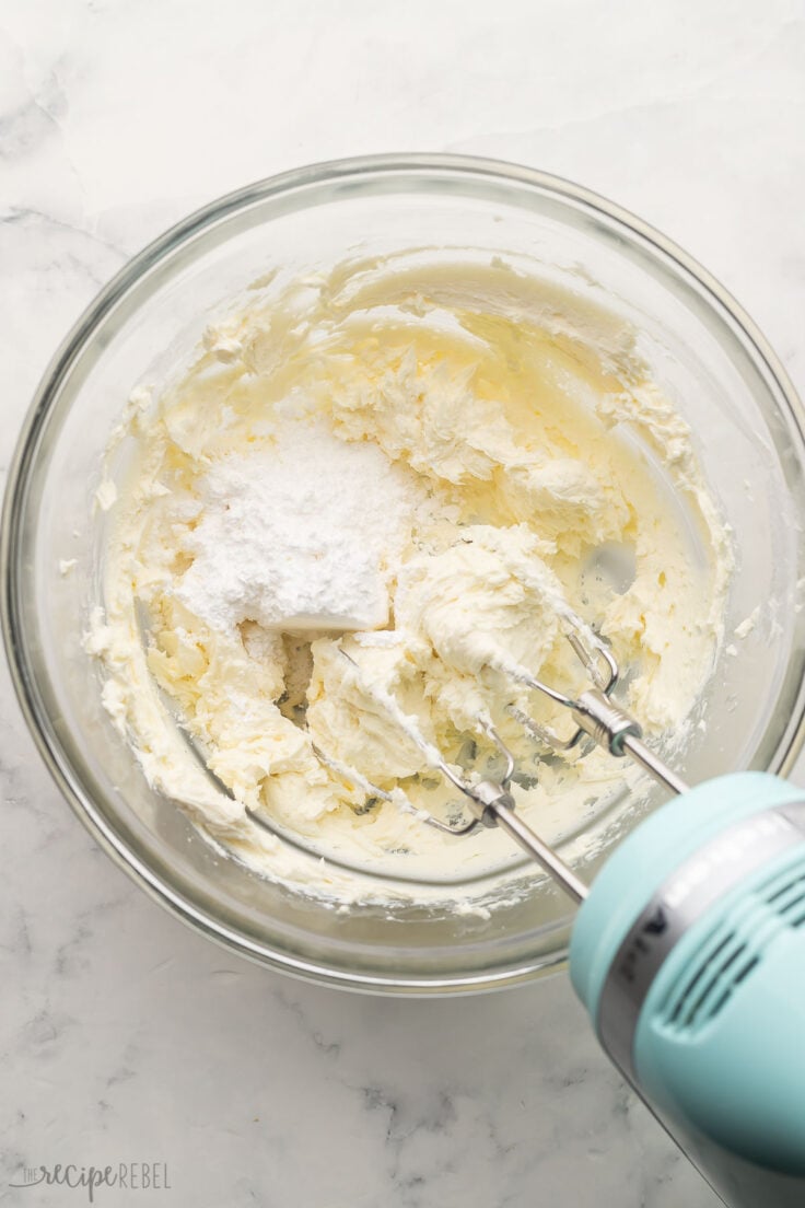 mixed cream cheese in a glass bowl with powdered sugar added.