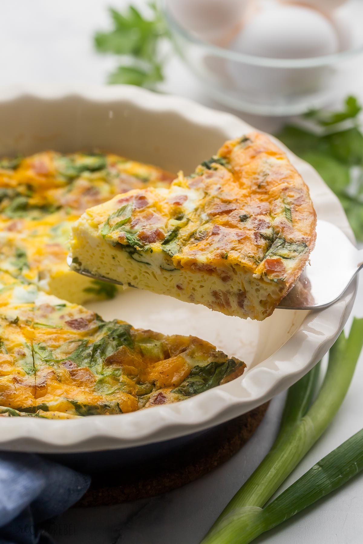 Side view of a slice of Crustless Quiche being lifted from the dish.