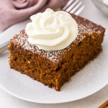 a piece of gingerbread and whipped cream on a white plate.