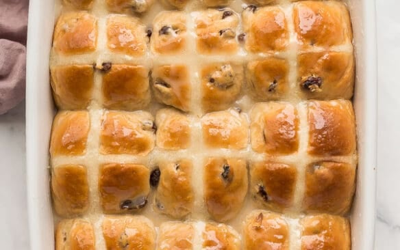 overhead image of hot cross buns in white baking dish with glaze