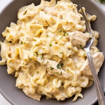 grey plate with chicken and noodles and fork.