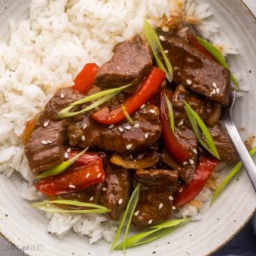 close up of mongolian beef on rice topped with sesame seeds.