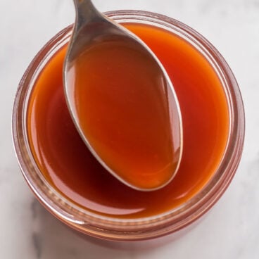 overhead image of sweet and sour sauce in small jar with spoon