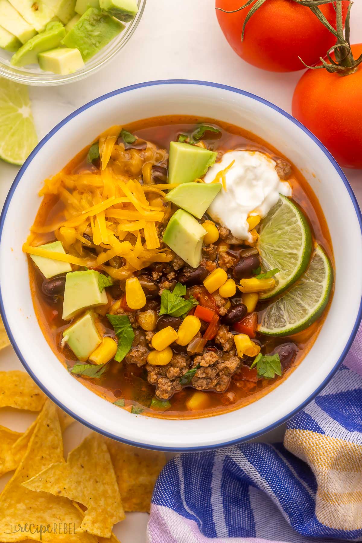 bowl filled with taco soup and topping with chips and tomatoes beside.